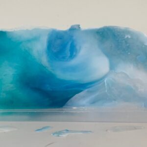 Available, July, 2025. A translucent blue and white soap bar with swirls, displayed on a white surface with droplets visible.